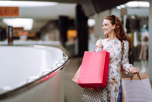 Modieuze vrouw met veelkleurige tassen in het winkelcentrum. De vreugde van consumptie.