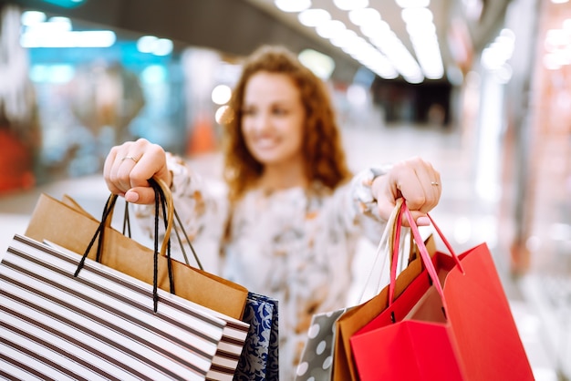 Modieuze vrouw met veelkleurige tassen in het winkelcentrum. De vreugde van consumptie.