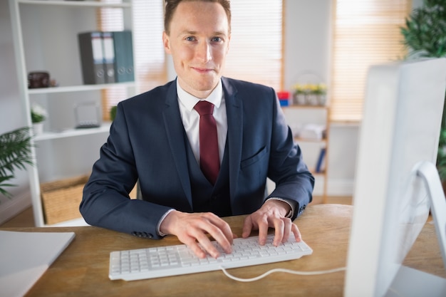 Modieuze zakenman die bij zijn bureau werkt