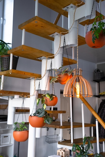 Modulaire metalen trap met houten treden in het witte interieur van een groen huis met potplanten, hangende bloempotlampenkap