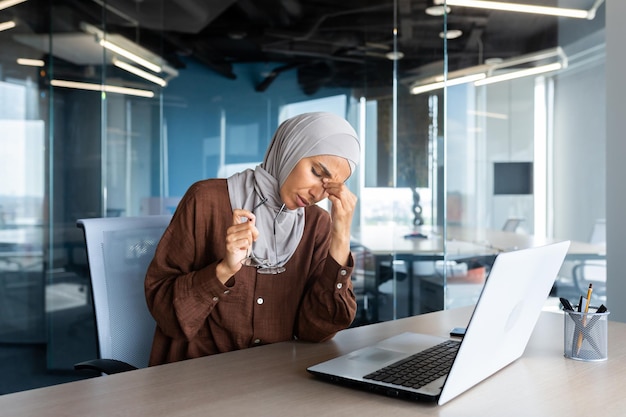 Moe en overwerkte zakenvrouw in hijab op de werkplek moslimvrouw die ogen masseert met een bril