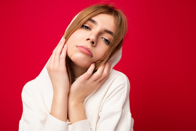 Moe jonge mooie donkere blonde vrouw met oprechte emoties geïsoleerd op de achtergrond muur met copy