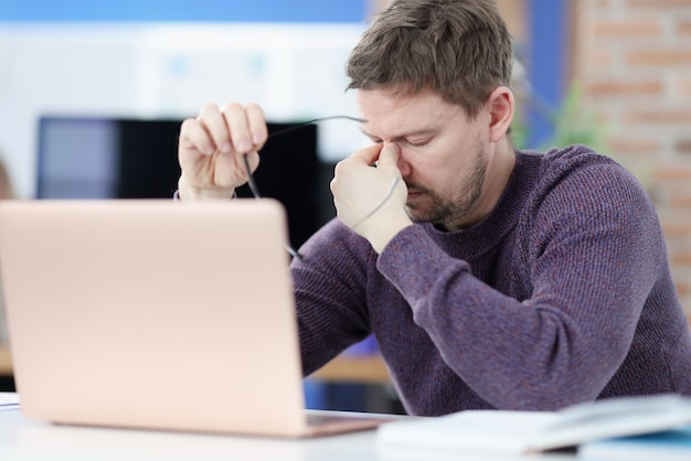 Moe man plaatsing voor laptop scherm en bril in handen te houden