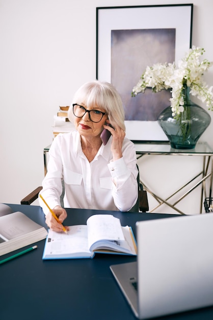 Moe senior mooie grijze haren vrouw in witte blouse werken op laptop in office