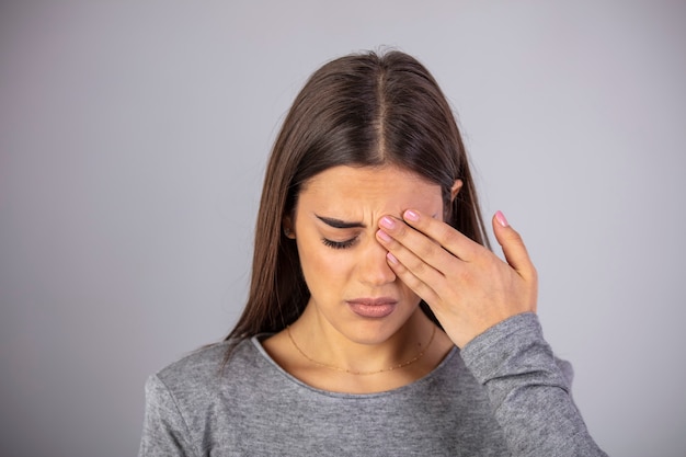 Foto moe uitgeput benadrukt vrouw die lijdt aan sterke oogpijn.