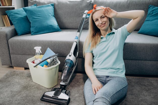 Foto moe vrouw ontspannen op de vloer na het schoonmaken van eigen appartement