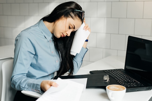 Moe vrouw zit aan bureau in office