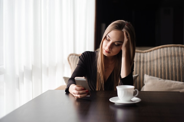 Moe zakenvrouw werken met mobiele telefoon tijdens een pauze.