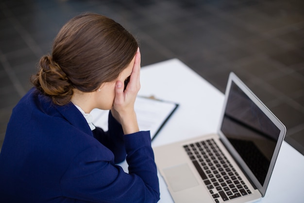 Moe zakenvrouw zit aan bureau met laptop