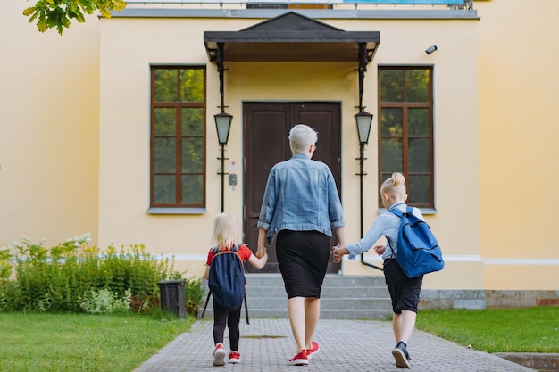 Moeder begeleidt kinderen hand in hand naar school