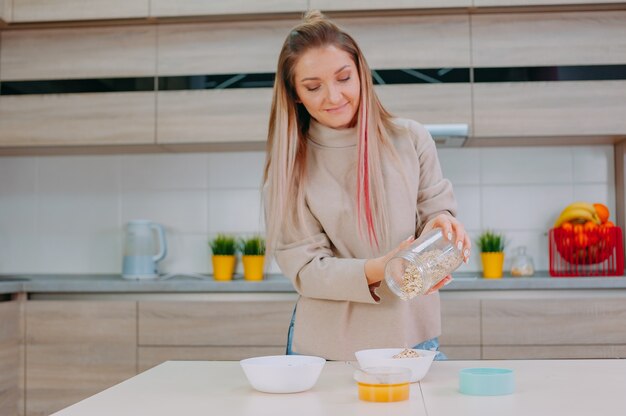 Moeder bereidt havermout met honing in de keuken.