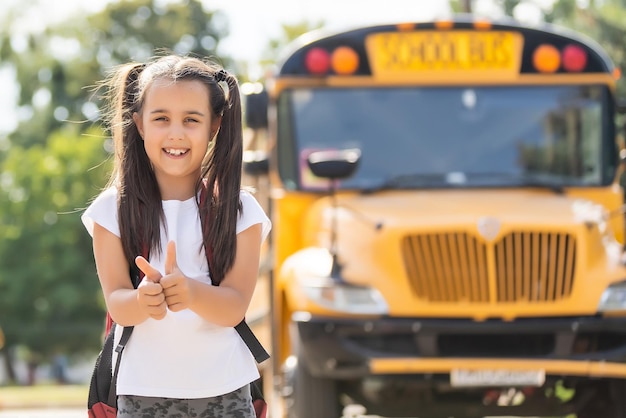 Moeder brengt haar dochter naar school in de buurt van de schoolbus. terug naar school