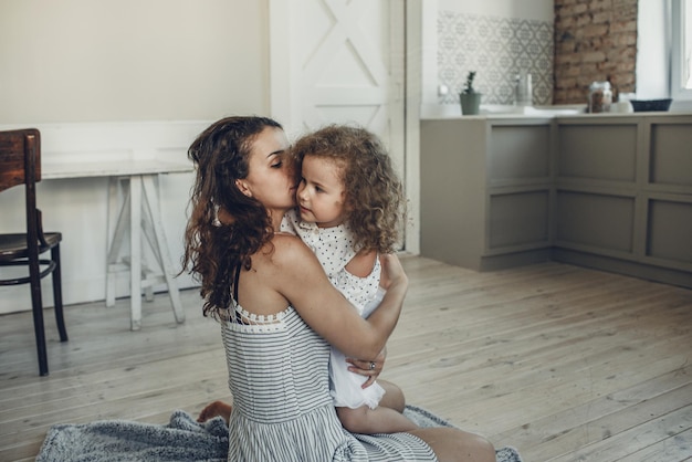 Moeder brengt tijd thuis door met haar dochter Schattige kleine dochter knuffelt haar vrolijke jonge moeder