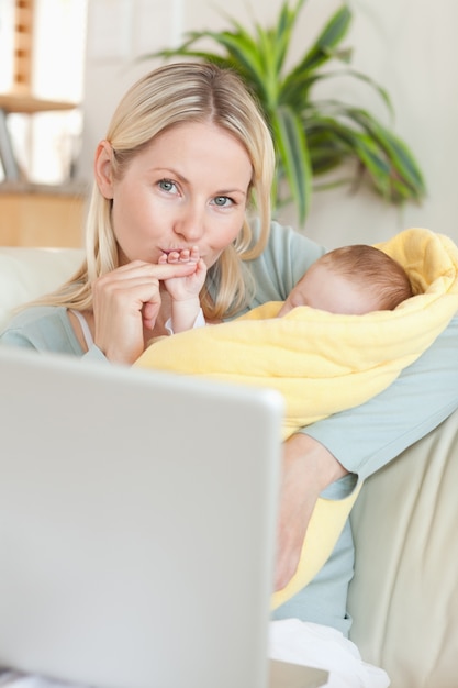 Foto moeder die de hand van haar baby kust terwijl het zitten op de bank