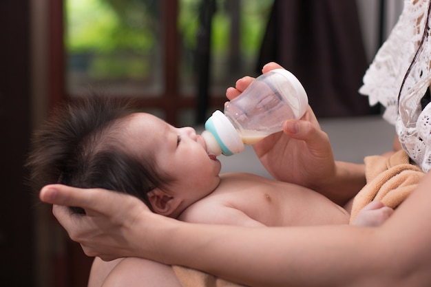 Moeder die en Aziatische pasgeboren baby van fles houden voeden.