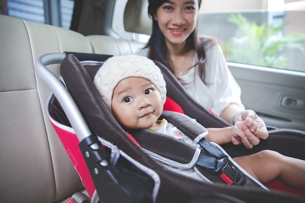 Moeder die haar baby in de autostoel beveiligt in haar auto