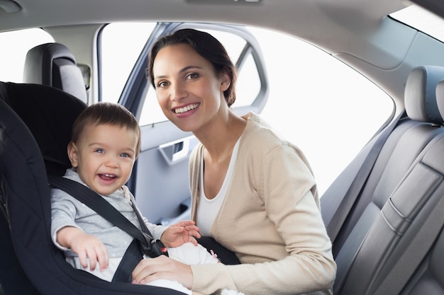 Moeder die haar baby in de autozetel beveiligt