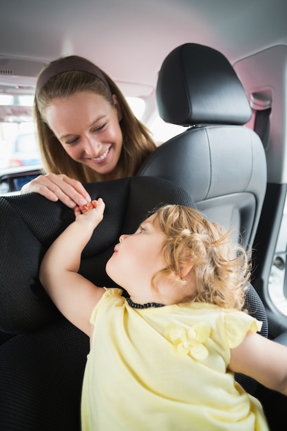 Moeder die haar baby in de autozetel controleert