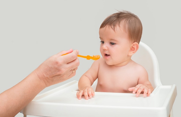 Moeder die haar baby voedt met een kleine lepel