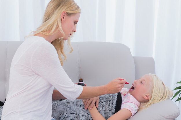 Moeder die haar dochtergeneeskunde op een lepel geeft