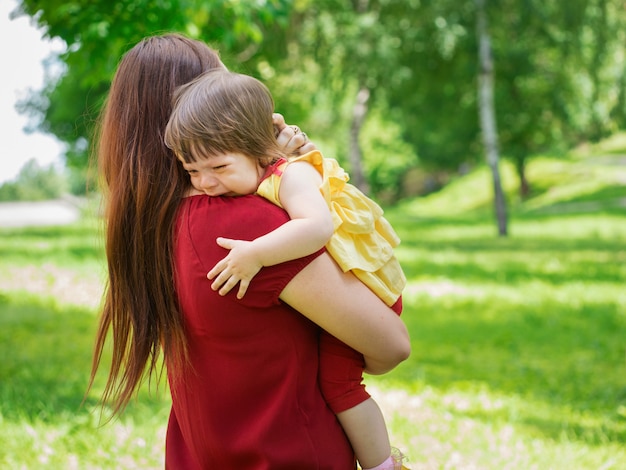 Moeder die haar huilend oud babymeisje van één jaar met tranen dicht tegenhoudt