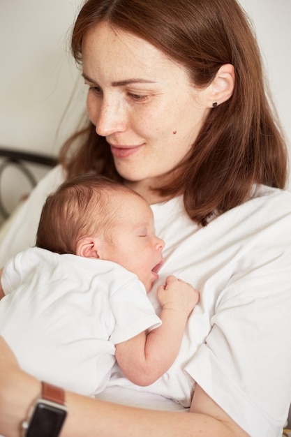 Moeder die haar pasgeboren baby vasthoudt Thuisportret van pasgeboren baby en moeder Samen genieten van tijd