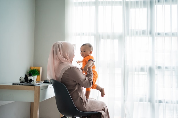 Moeder die haar zoon op schoot tijdens het spelen zittend op de stoel