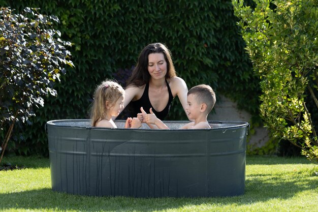 Moeder die plezier heeft met kinderen in een buitenbad in de achtertuin in de zomer