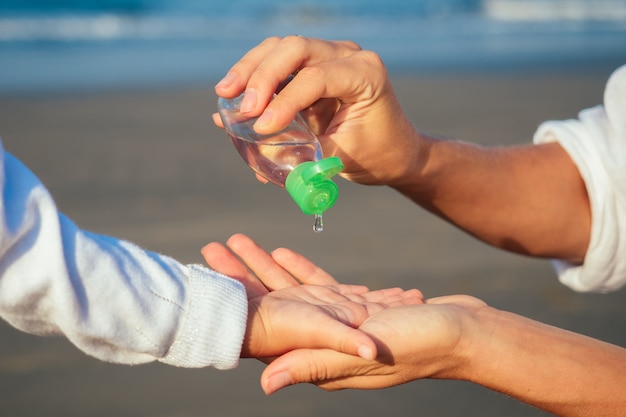 Moeder dochter druipend op hand antisepticum op het strand