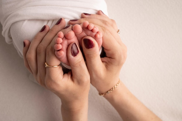 Moeder doet massage op haar babyvoet Close-up babyvoeten in moederhanden Preventie van ontwikkeling van platte voeten spiertonusdysplasie Familie liefde zorg en gezondheidsconcepten Studio macro