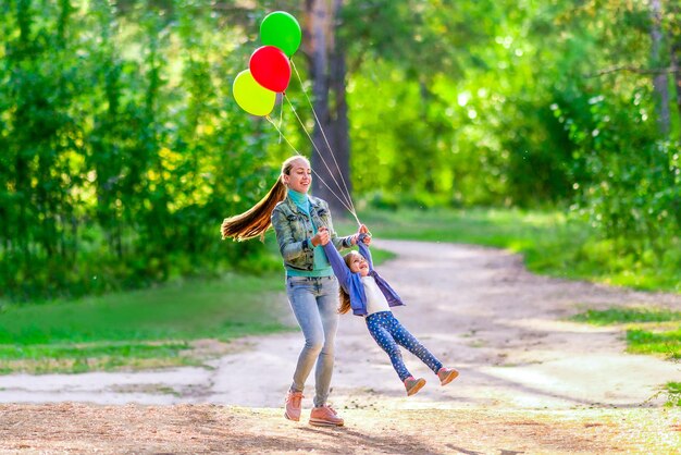 Moeder draait haar dochter terwijl ze haar handen vasthoudt Tijdens een wandeling in het bos Zonnige zomerdag