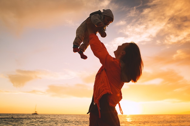 Moeder en baby bij zonsondergang strand oceaan Vrouw en kind samen op zee Gelukkige familie achtergrond