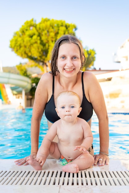 Moeder en baby in het zwembad met waterglijbanen in de zomer veel plezier met zwemmen, ontspannen en tijd doorbrengen met het gezin op vakantie