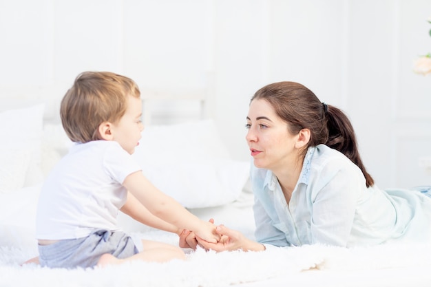 Moeder en baby praten thuis op het bed, het concept van de relatie tussen ouders en kinderen