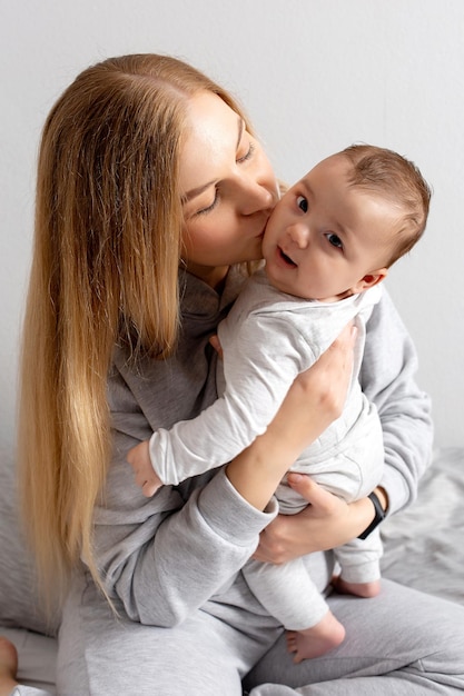 Moeder en baby spelen op het bed Moeder en zoon gelukkig gezin mooi blond meisje en schattige baby thuis