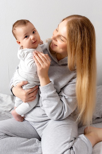 Moeder en baby spelen op het bed Moeder en zoon gelukkig gezin mooi blond meisje en schattige baby thuis