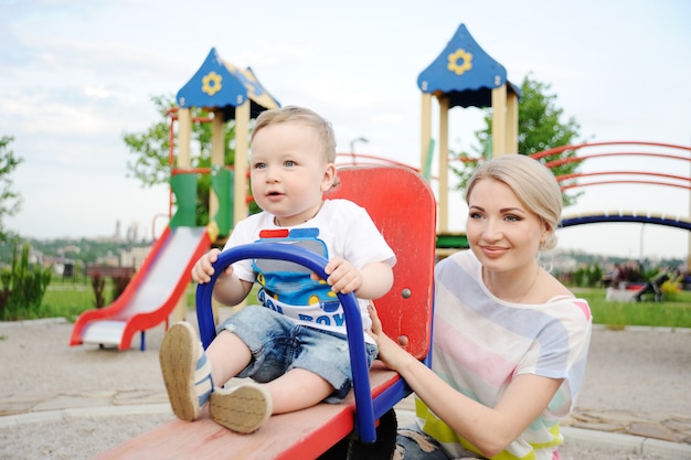 Moeder en baby zoon spelen in de speeltuin