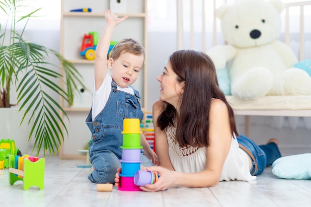 Moeder en babyjongen spelen thuis met educatief speelgoed in de kinderkamer Een gelukkig liefdevol gezin