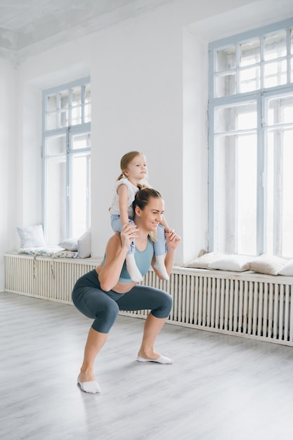 Moeder en babymeisje doen oefeningen samen in de sportschool