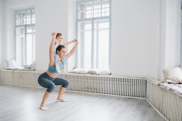 Moeder en babymeisje doen oefeningen samen in de sportschool