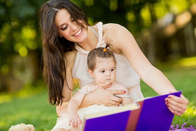 Moeder en babymeisje met boek in het park