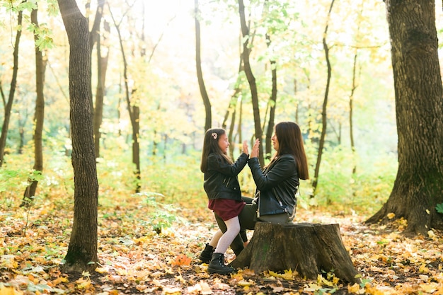 Moeder en dochter brengen samen tijd door in het herfstgeel parkseizoen en het concept voor alleenstaande ouders