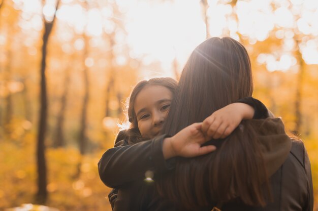 Moeder en dochter brengen samen tijd door in het herfstgeel parkseizoen en het concept voor alleenstaande ouders