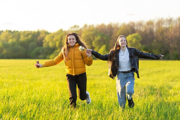 Moeder en dochter casual gekleed rennen in het veld bij prachtige lentezonsondergang