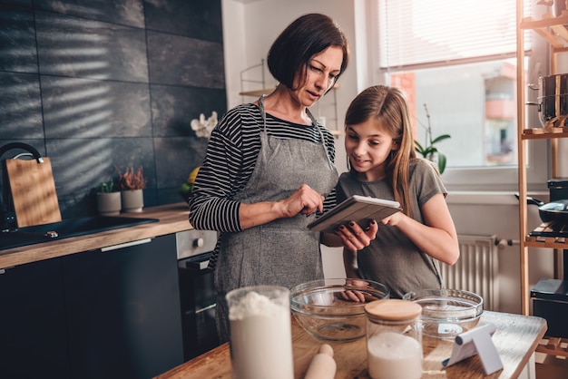 Moeder en dochter die appeltaartrecept zoeken op de tablet