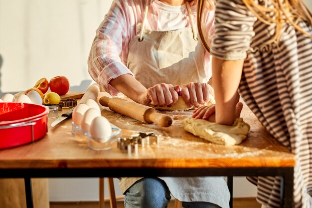 moeder en dochter die deeg voor zelfgemaakt dessert in keuken kneden, onderwijzen en leren