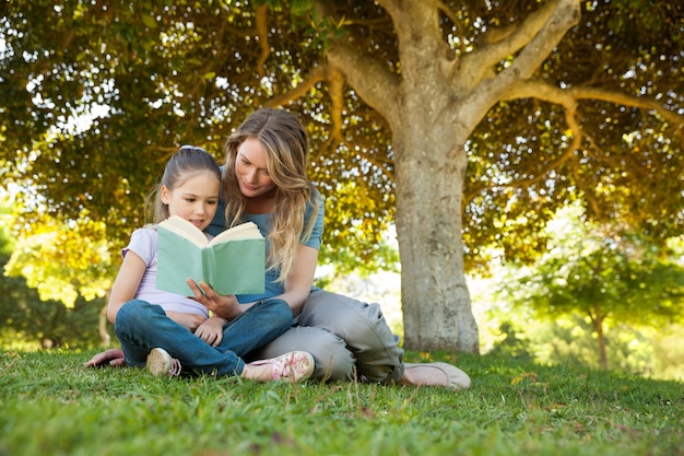 Moeder en dochter die een boek lezen bij park