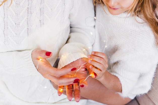 Moeder en dochter die een slinger houden die voor Kerstmis voorbereidingen treft