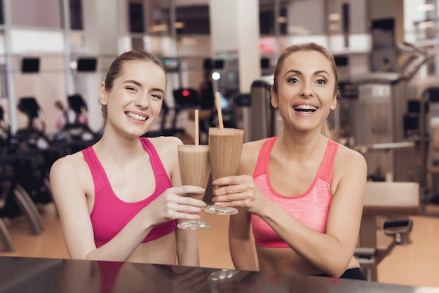 Moeder en dochter die eiwitschokken drinken bij de sportschool