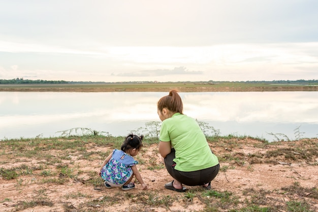 Moeder en dochter die en rivier spelen bekijken. ontspanningstijd en geluk